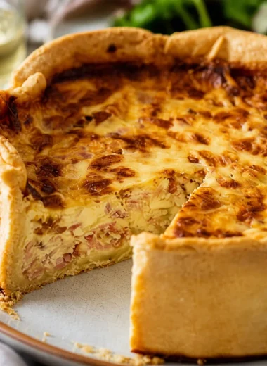 Slice of Traditional French Quiche Lorraine with crispy bacon and creamy filling.