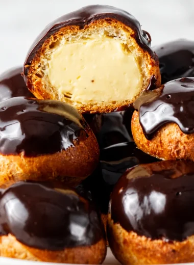 Deliciously Rich French Profiteroles filled with creamy custard and topped with chocolate sauce.