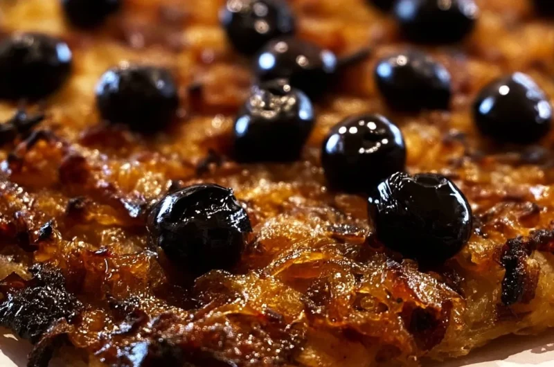 A slice of traditional Pissaladière topped with caramelized onions and olives.