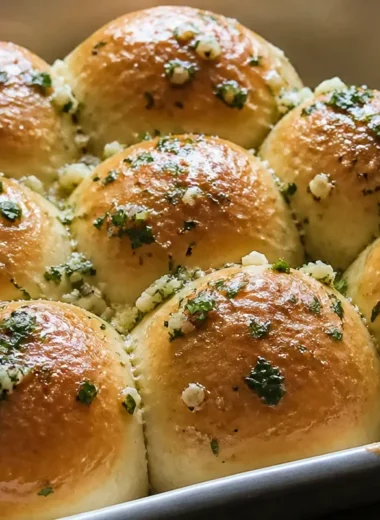 Freshly baked garlic butter bread rolls resting on a wooden table.