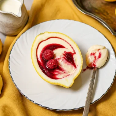 Lemon cream dessert topped with raspberry sauce on a white plate