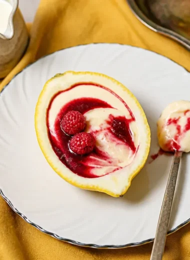 Lemon cream dessert topped with raspberry sauce on a white plate