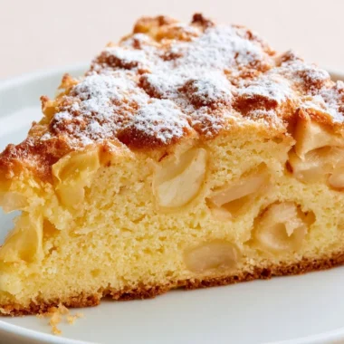 Slice of traditional French apple cake topped with fresh apple slices