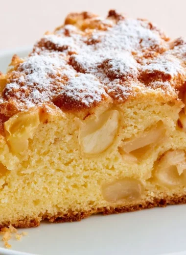 Slice of traditional French apple cake topped with fresh apple slices